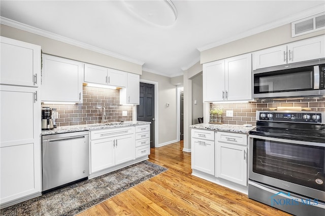 524 Sutton Pl, Findlay, OH 45840 - kitchen featuring appliances with stainless steel finishes, crown molding, white cabinets, a sink, and light wood-type flooring