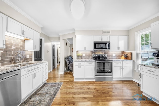 524 Sutton Pl, Findlay, OH 45840 - kitchen featuring appliances with stainless steel finishes, a sink, tasteful backsplash, white cabinets, and ornamental molding