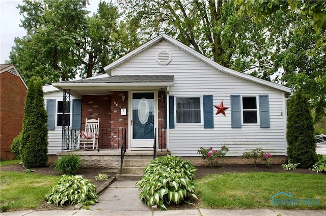 663 W Summit St, Fostoria, OH 44830 - view of front facade featuring a porch, brick siding, and a front lawn