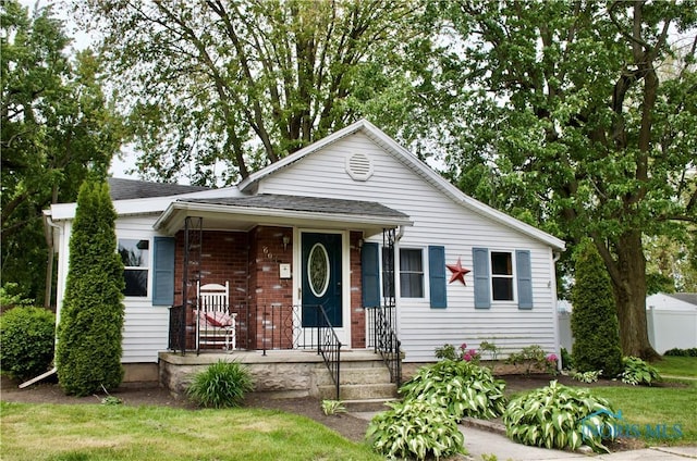663 W Summit St, Fostoria, OH 44830 - view of front facade with a porch, a shingled roof, and brick siding