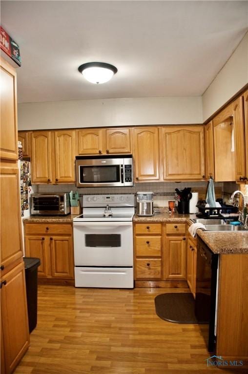 663 W Summit St, Fostoria, OH 44830 - kitchen featuring stainless steel microwave, white electric stove, a sink, light wood-type flooring, and decorative backsplash