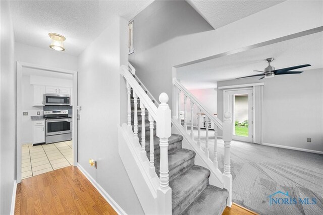 117 Freedom Ln, Waterville, OH 43566 - stairs with a textured ceiling, a ceiling fan, baseboards, and wood finished floors
