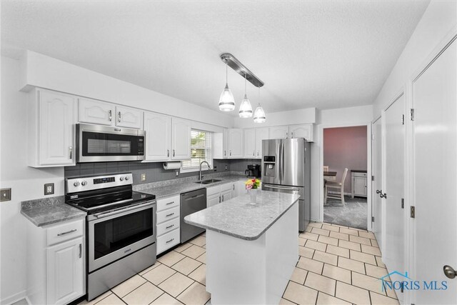 117 Freedom Ln, Waterville, OH 43566 - kitchen featuring stainless steel appliances, a sink, white cabinetry, a kitchen island, and a textured ceiling