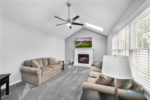 117 Freedom Ln, Waterville, OH 43566 - carpeted living area with ceiling fan, vaulted ceiling, a lit fireplace, baseboards, and a skylight