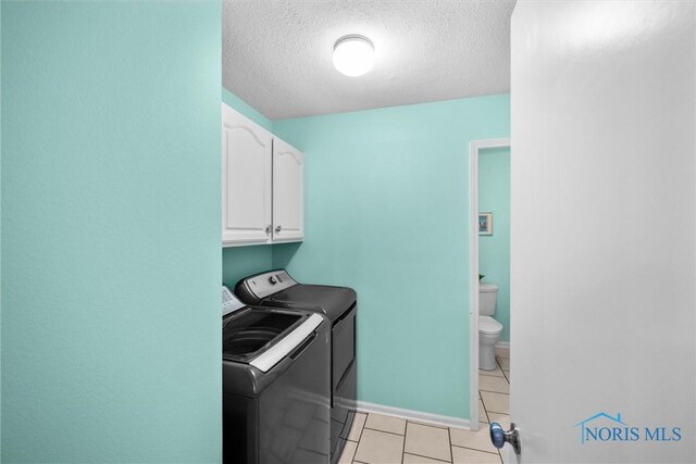 117 Freedom Ln, Waterville, OH 43566 - washroom featuring cabinet space, washer and dryer, a textured ceiling, light tile patterned floors, and baseboards