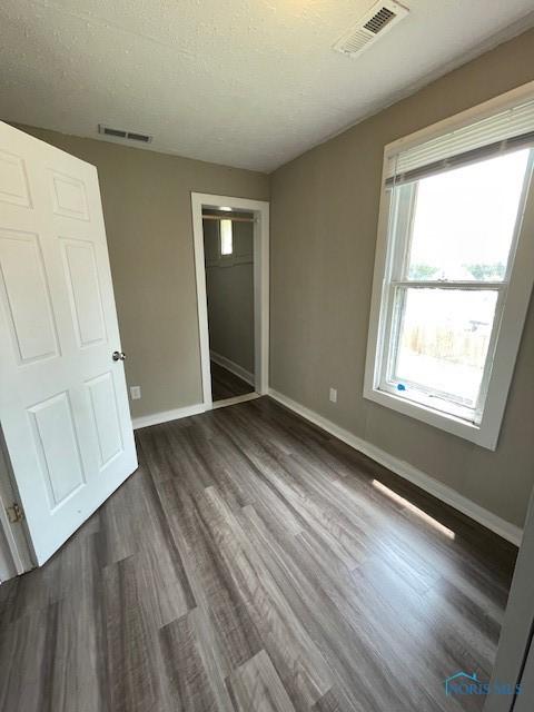 821 Vinton St, Toledo, OH 43609 - unfurnished bedroom with baseboards, dark wood-style flooring, a closet, and a textured ceiling