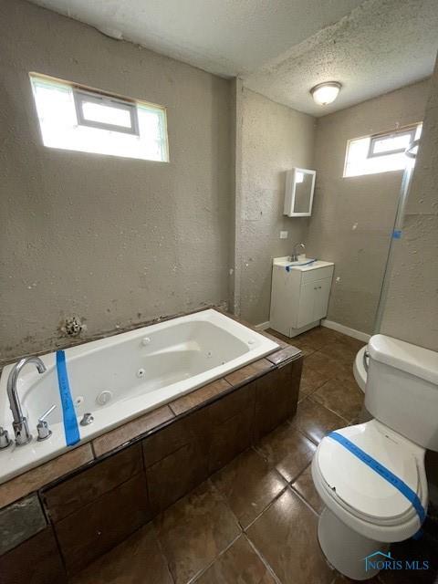 821 Vinton St, Toledo, OH 43609 - bathroom featuring toilet, healthy amount of natural light, a whirlpool tub, tile patterned floors, and a textured ceiling