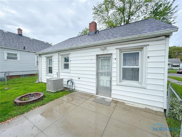 4635 Vermaas Ave, Toledo, OH 43612 - back of property featuring central AC unit, a patio area, a chimney, a fire pit, and a shingled roof