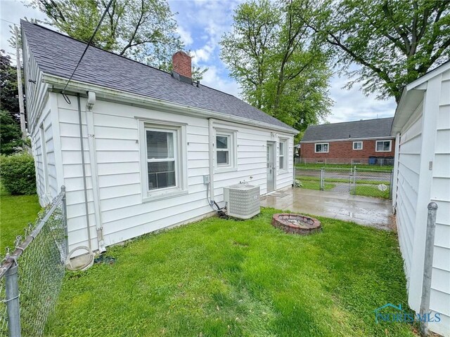 4635 Vermaas Ave, Toledo, OH 43612 - back of property featuring central air condition unit, a chimney, roof with shingles, and an outdoor fire pit