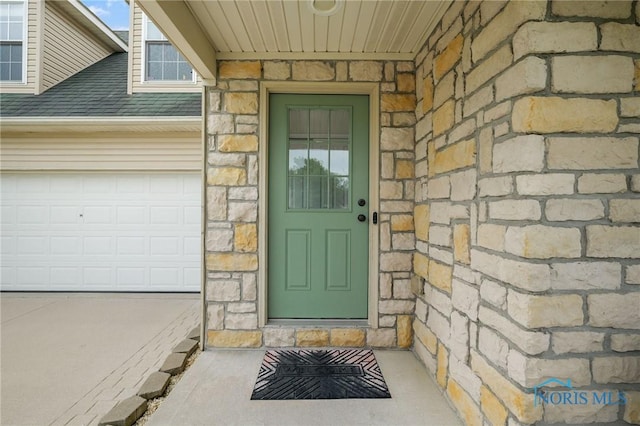 819 Wood Sorrel Ln, Perrysburg, OH 43551 - view of exterior entry featuring stone siding, a garage, and a shingled roof