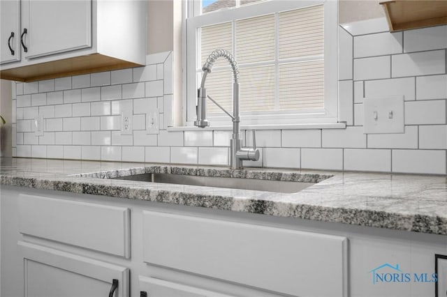819 Wood Sorrel Ln, Perrysburg, OH 43551 - kitchen featuring a sink, tasteful backsplash, light stone countertops, and white cabinets