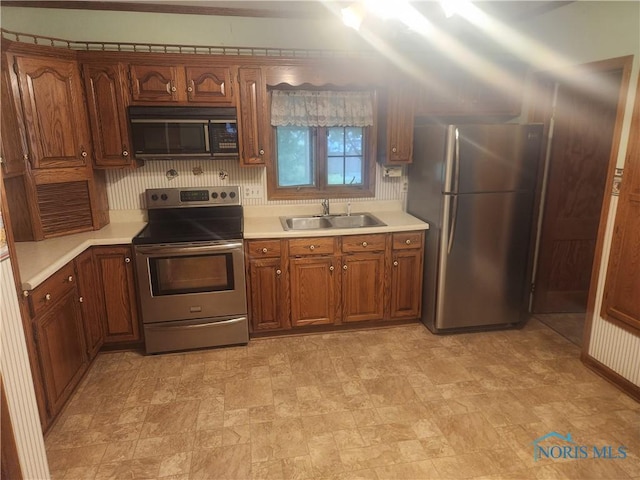 104 E S St, Middle Point, OH 45863 - kitchen featuring stainless steel appliances, a sink, light countertops, and brown cabinetry
