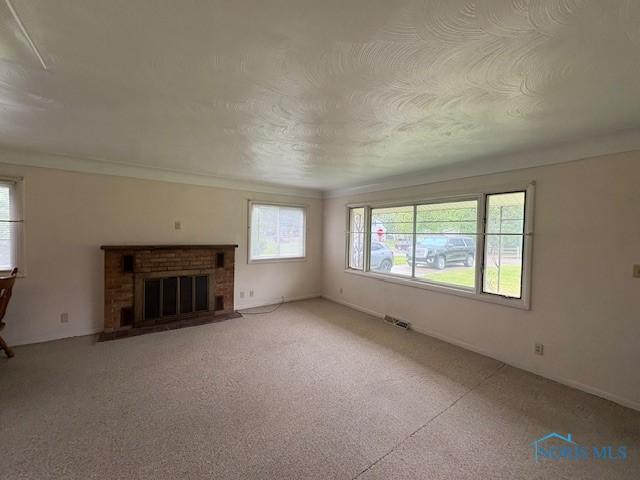 23695 E Second St, Grand Rapids, OH 43522 - unfurnished living room featuring plenty of natural light, a fireplace, and light colored carpet