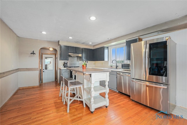 22227 US Highway 20a, West Unity, OH 43570 - kitchen featuring appliances with stainless steel finishes, arched walkways, under cabinet range hood, light countertops, and light wood-style floors