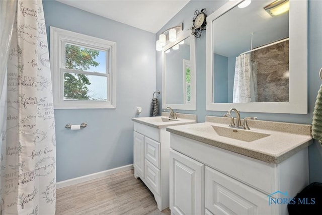 219 Illinois Dr, Bryan, OH 43506 - bathroom with two vanities, baseboards, wood finished floors, and a shower with curtain