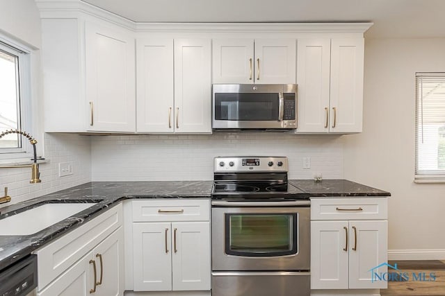 1048 Richland St, Maumee, OH 43537 - kitchen featuring appliances with stainless steel finishes, a sink, white cabinets, dark stone countertops, and backsplash