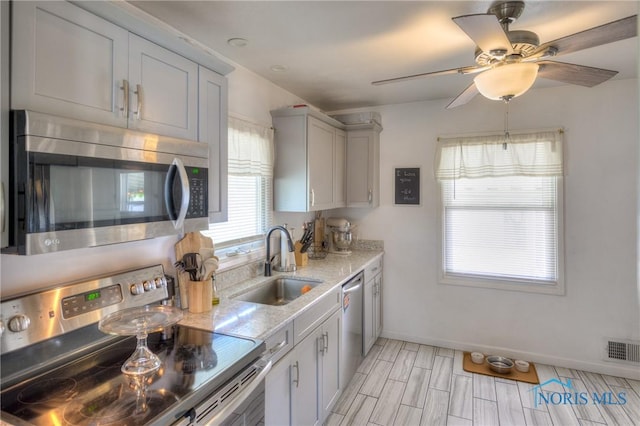 1367 Junior Dr, Maumee, OH 43537 - kitchen featuring stainless steel appliances, a sink, baseboards, light stone counters, and ceiling fan