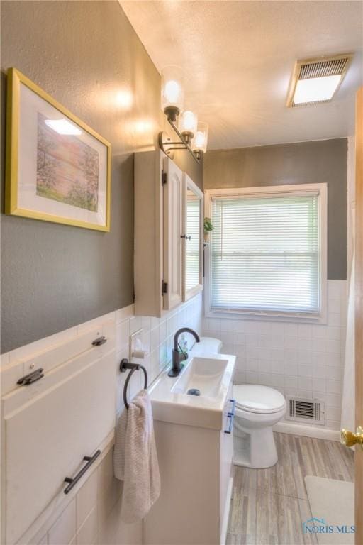 1367 Junior Dr, Maumee, OH 43537 - bathroom featuring tile walls, vanity, wood finished floors, and toilet