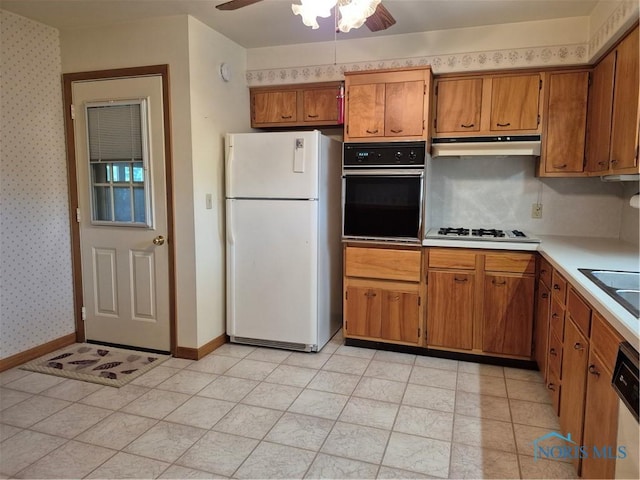 1100 Cherry Ln, Findlay, OH 45840 - kitchen featuring freestanding refrigerator, oven, under cabinet range hood, brown cabinetry, and ceiling fan