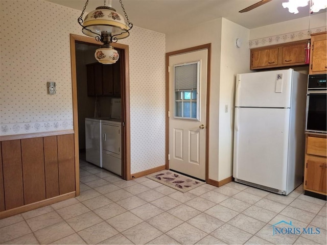1100 Cherry Ln, Findlay, OH 45840 - kitchen featuring freestanding refrigerator, wall oven, wallpapered walls, brown cabinetry, and washing machine and dryer