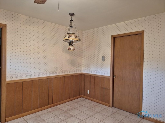 1100 Cherry Ln, Findlay, OH 45840 - unfurnished dining area featuring wallpapered walls, wainscoting, a ceiling fan, and light tile patterned flooring