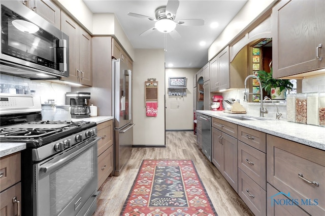2742 Sandalwood Ave, Toledo, OH 43614 - kitchen featuring stainless steel appliances, a sink, light wood finished floors, ceiling fan, and decorative backsplash