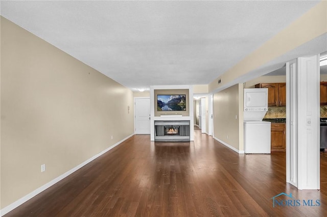 6640 Salisbury Rd Unit 212, Maumee, OH 43537 - unfurnished living room with stacked washer and clothes dryer, dark wood finished floors, and a lit fireplace