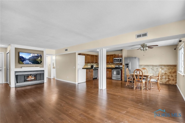 6640 Salisbury Rd Unit 212, Maumee, OH 43537 - living area with dark wood-style flooring, a ceiling fan, a wainscoted wall, a warm lit fireplace, and a textured ceiling