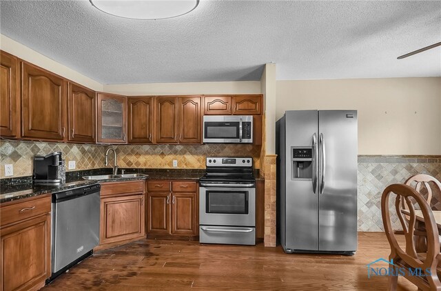 6640 Salisbury Rd Unit 212, Maumee, OH 43537 - kitchen with stainless steel appliances, dark wood-style floors, wainscoting, brown cabinetry, and glass insert cabinets