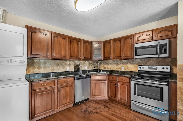 6640 Salisbury Rd Unit 212, Maumee, OH 43537 - kitchen with stainless steel appliances, stacked washing machine and dryer, dark wood-style flooring, brown cabinets, and a textured ceiling