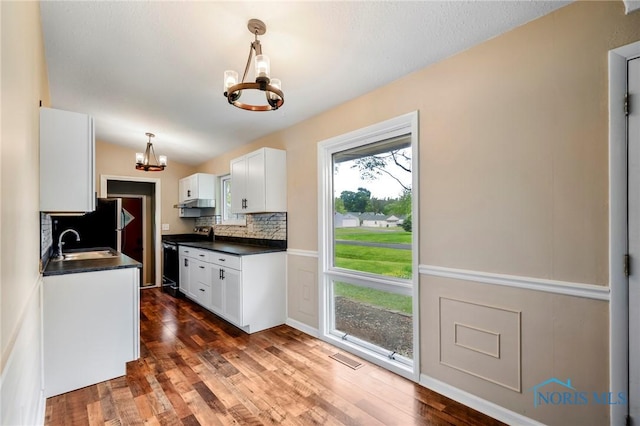 1765 Newport Ave, Toledo, OH 43613 - kitchen with a chandelier, electric range, dark countertops, white cabinetry, and backsplash