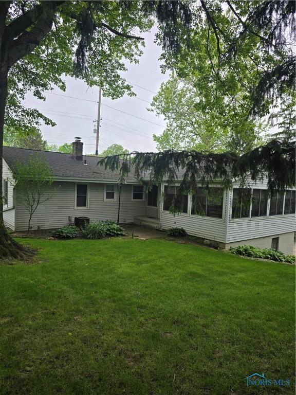 1501 Tiffin Rd, Fremont, OH 43420 - rear view of house with a sunroom, a chimney, a yard, and a patio area