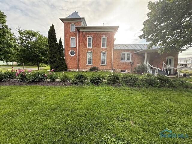 206 W Main St, Fayette, OH 43521 - rear view of house featuring a standing seam roof, brick siding, a lawn, and metal roof