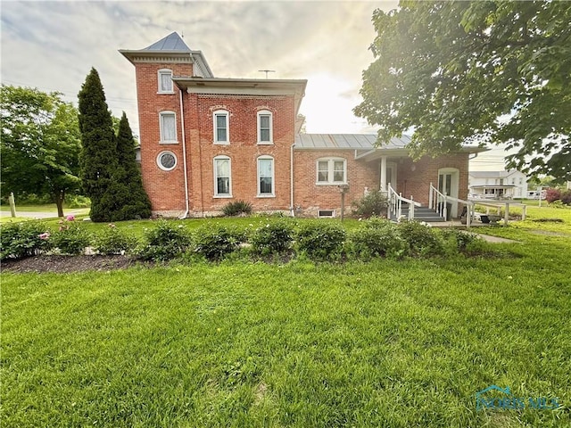 206 W Main St, Fayette, OH 43521 - rear view of property featuring a standing seam roof, a lawn, brick siding, and metal roof