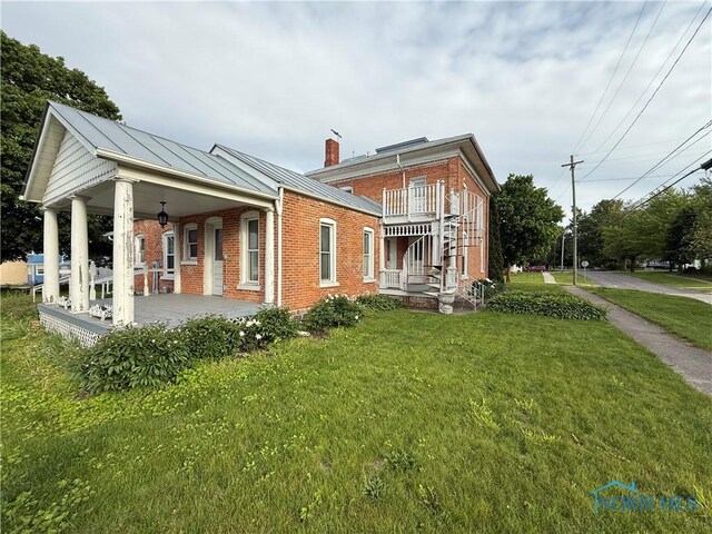 206 W Main St, Fayette, OH 43521 - rear view of property with brick siding, a porch, a lawn, and a chimney