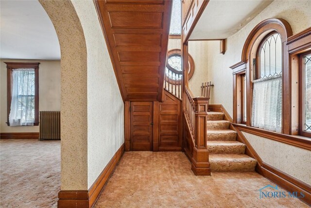 206 W Main St, Fayette, OH 43521 - staircase featuring carpet floors, arched walkways, radiator, baseboards, and wallpapered walls