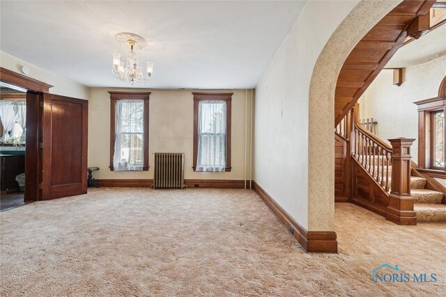 206 W Main St, Fayette, OH 43521 - unfurnished living room with radiator, carpet flooring, plenty of natural light, and a chandelier