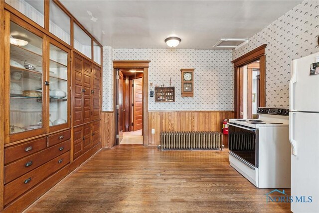 206 W Main St, Fayette, OH 43521 - kitchen featuring white appliances, radiator, wainscoting, wallpapered walls, and wood finished floors