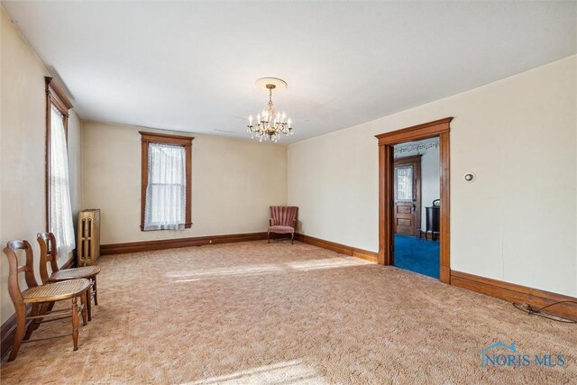 206 W Main St, Fayette, OH 43521 - empty room with radiator heating unit, a chandelier, baseboards, and carpet