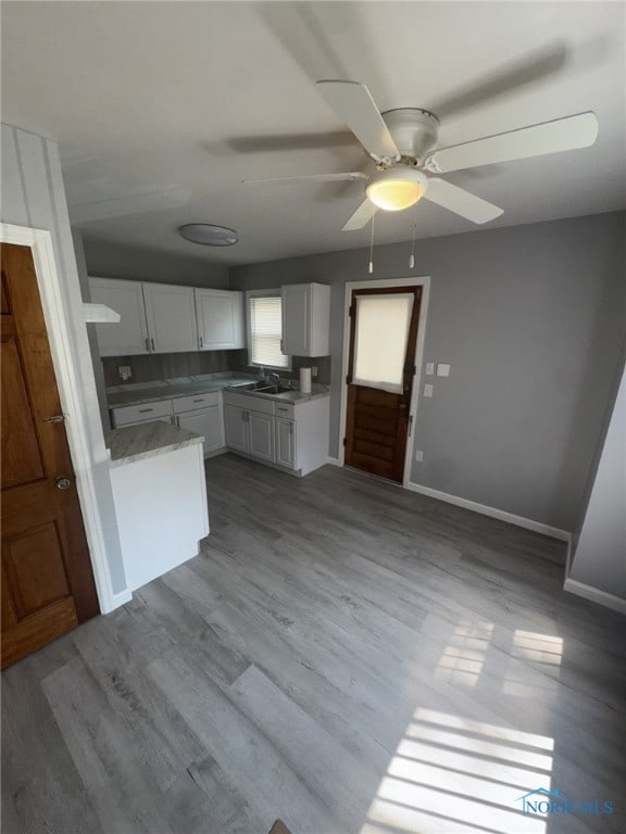 642 Brookley Blvd, Toledo, OH 43607 - kitchen with white cabinets, a ceiling fan, wood finished floors, and a sink