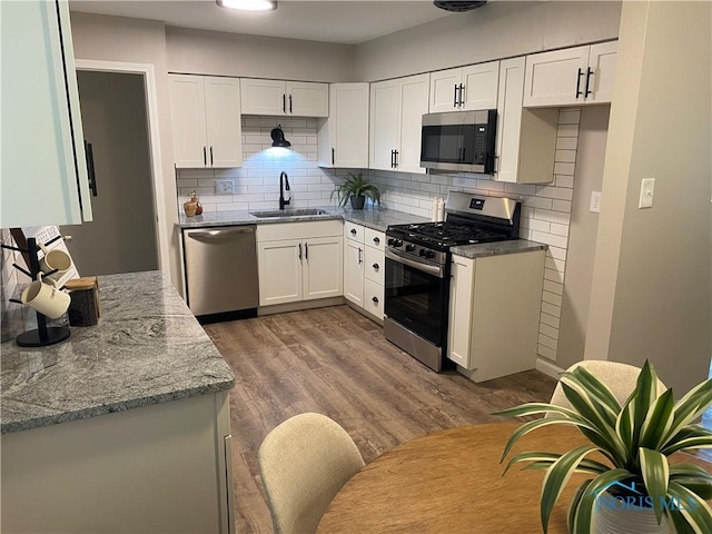 210 W William St, Maumee, OH 43537 - kitchen with stainless steel appliances, a sink, white cabinets, backsplash, and dark wood finished floors