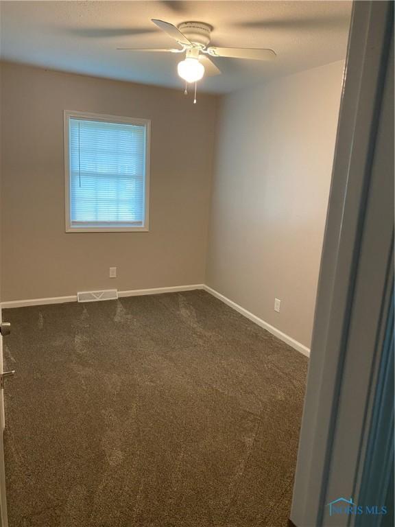 210 W William St, Maumee, OH 43537 - empty room with baseboards, ceiling fan, and dark colored carpet