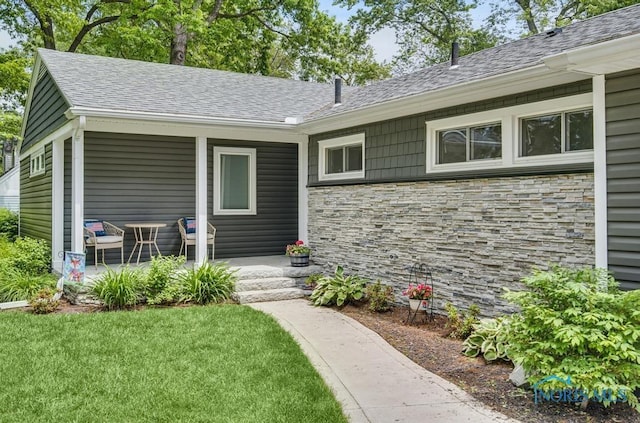 2714 W Rockridge Cir, Toledo, OH 43606 - property entrance with stone siding, covered porch, a shingled roof, and a yard