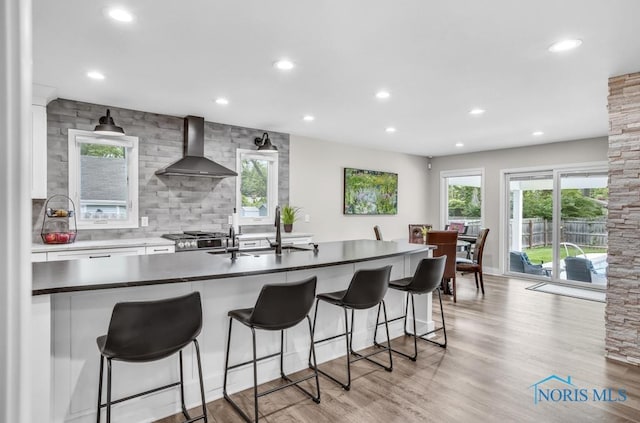 2714 W Rockridge Cir, Toledo, OH 43606 - kitchen featuring wall chimney exhaust hood, recessed lighting, white cabinetry, healthy amount of natural light, and stainless steel gas range