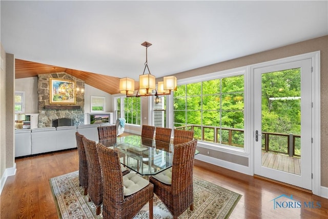 1860 Watermill Ln, Perrysburg, OH 43551 - dining room with a fireplace, a chandelier, vaulted ceiling, wood finished floors, and baseboards