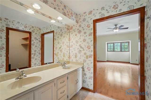 4820 Olde Meadow Ln, Sylvania, OH 43560 - bathroom with wallpapered walls, double vanity, baseboards, ceiling fan, and wood finished floors