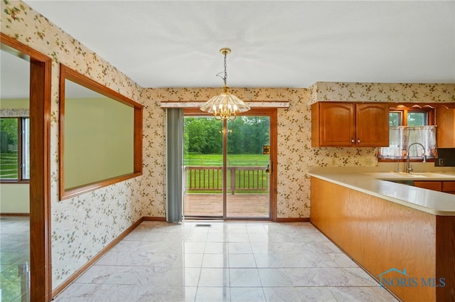 4820 Olde Meadow Ln, Sylvania, OH 43560 - kitchen with a chandelier, wallpapered walls, light countertops, baseboards, and brown cabinetry