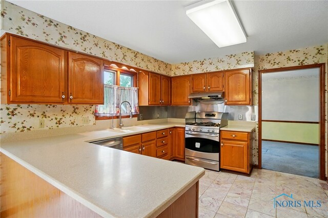4820 Olde Meadow Ln, Sylvania, OH 43560 - kitchen featuring stainless steel appliances, a sink, light countertops, brown cabinetry, and wallpapered walls