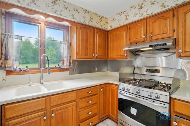 4820 Olde Meadow Ln, Sylvania, OH 43560 - kitchen featuring range with gas stovetop, under cabinet range hood, a sink, brown cabinetry, and light countertops