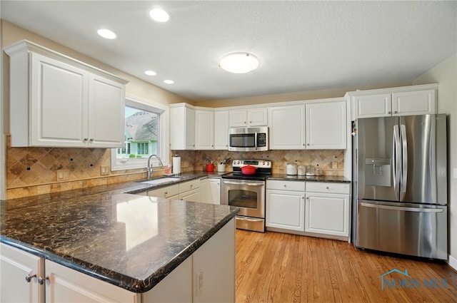 8420 Willow Glen Ct, Holland, OH 43528 - kitchen with stainless steel appliances, a sink, white cabinetry, a peninsula, and light wood-style floors